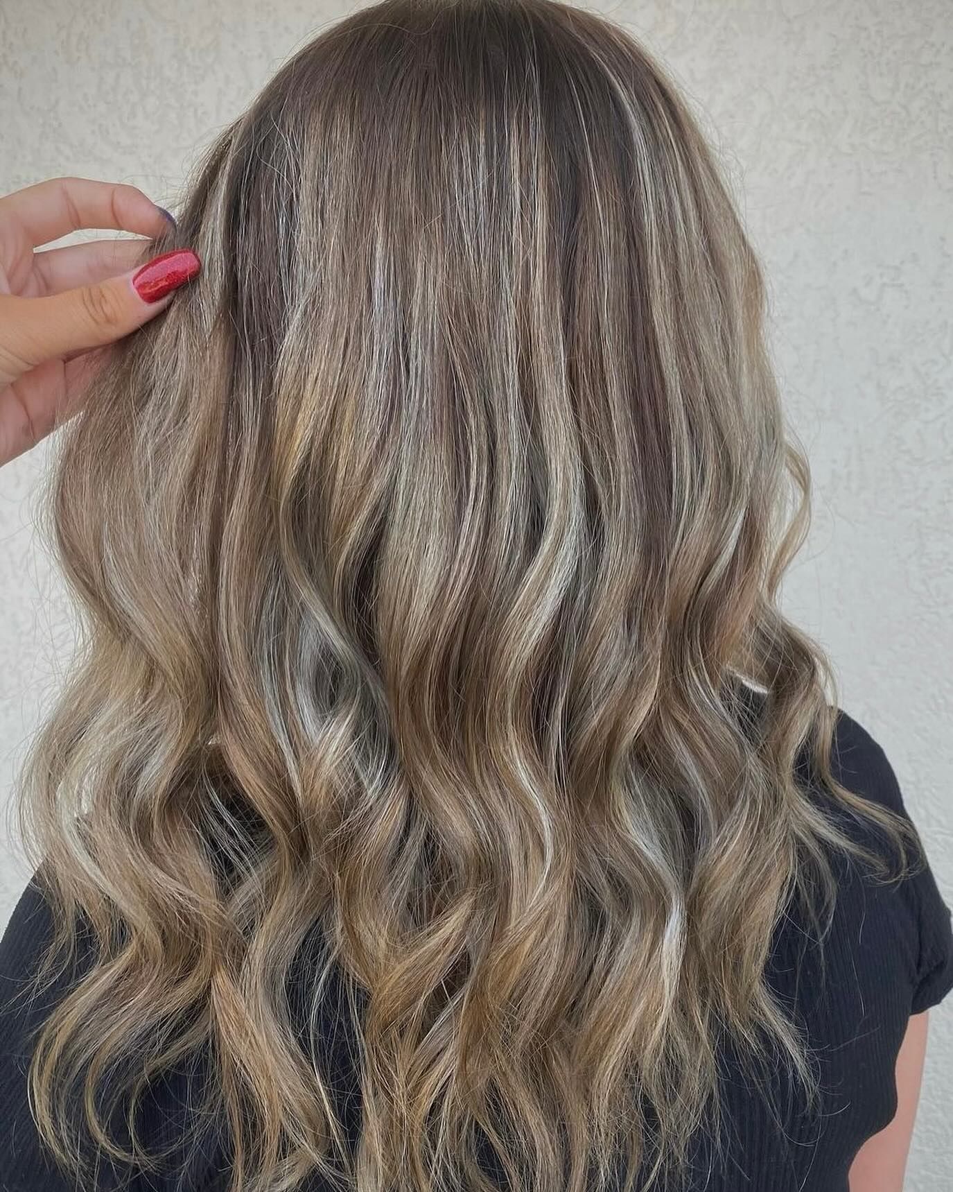 A person's long, wavy, highlighted hair with visible crimped texture, shown from behind.